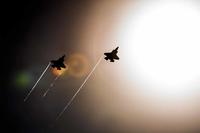 A pair of F-35 Lightning IIs pass under the sun while doing maneuvers to the Eglin Air Force Base runway.